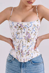 Woman wearing a floral print corset top with blue ribbon accents and a sweetheart neckline, paired with blue denim jeans.