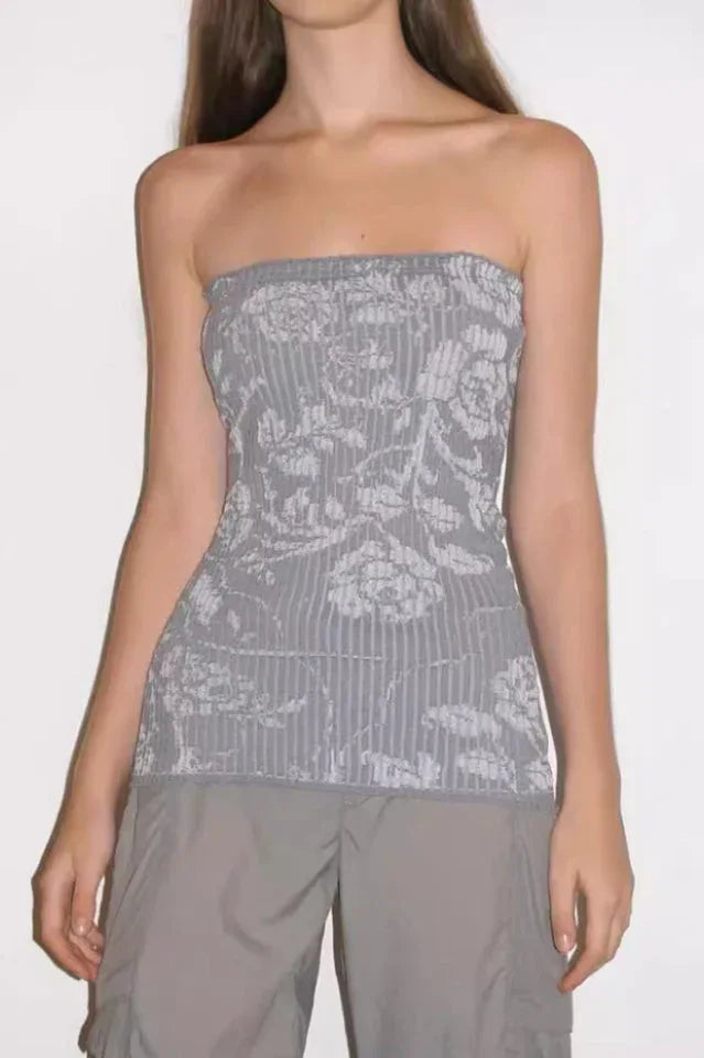 Young woman wearing a light gray strapless top with a white floral pattern and vertical ribbing, paired with gray cargo pants.