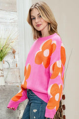 Woman wearing a pink crew neck sweater with an orange and white floral print, shown from the side.