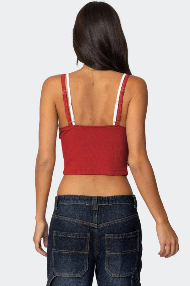 Back view of a red cropped tank top with lace trim and adjustable straps, paired with dark wash jeans.