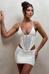 Woman wearing a white crochet knit corset top and matching mini skirt, front view
