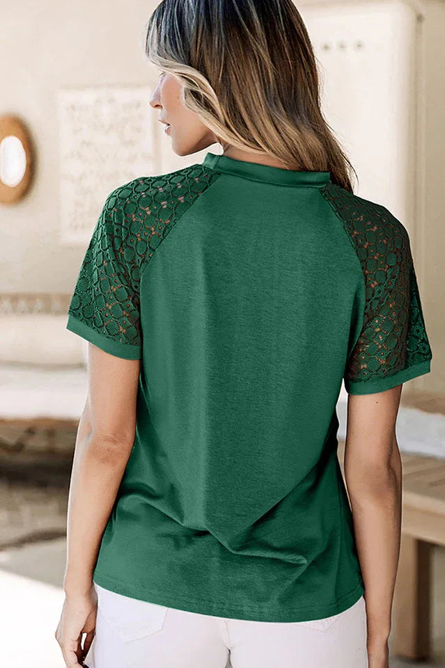 Back view of a woman wearing a green t-shirt with lace sleeves and white shorts.