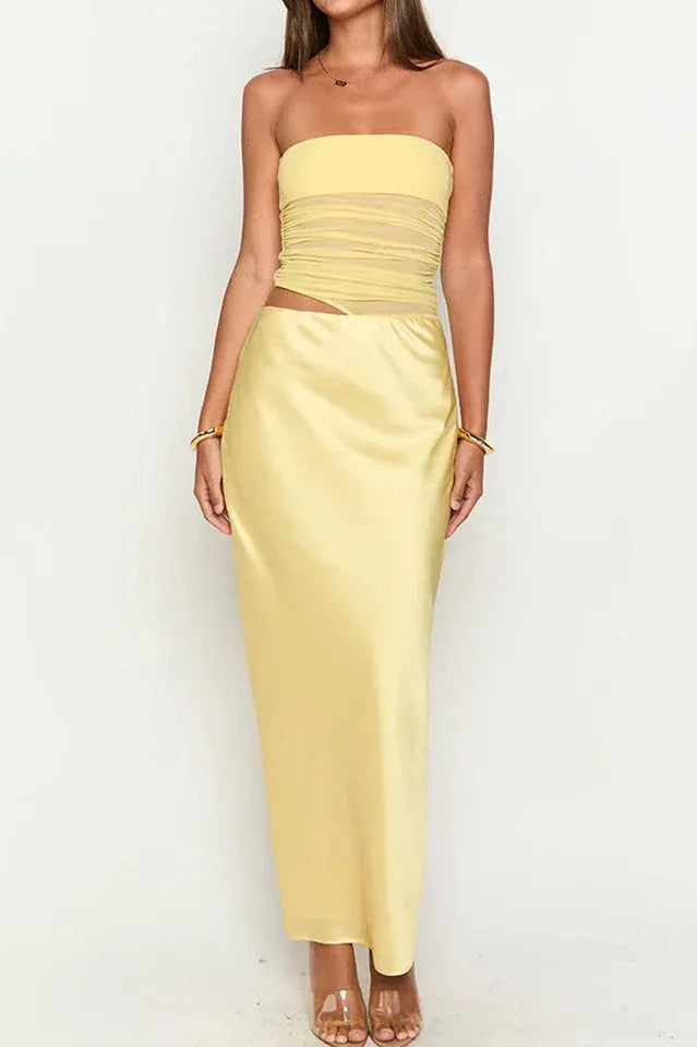Front view of a woman wearing a yellow strapless satin maxi dress with a ruched bodice and a high slit, against a white background.