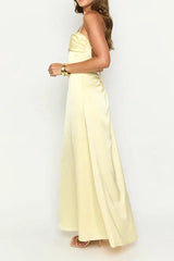 side view of a woman wearing a pale yellow satin maxi dress with spaghetti straps and a sweetheart neckline, showing the slit