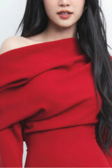 Close-up of the draped neckline and off-the-shoulder design of a red dress.