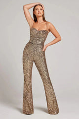 Woman wearing a gold sequined jumpsuit with a sweetheart neckline and wide legs, posing with one arm raised.