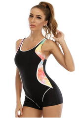 Side view of a woman in a black one-piece swimsuit featuring tie-dye accents.