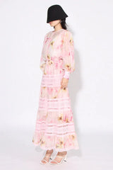 Woman wearing a pink floral print maxi dress from the side