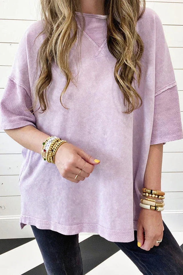 Woman wearing a lavender acid wash oversized t-shirt with stacked bracelets