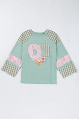 Flat lay of a mint green long-sleeved top with a heart applique and plaid patchwork sleeves.