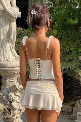 Rear view of a woman wearing a white lace-up corset top and ruffled skirt.
