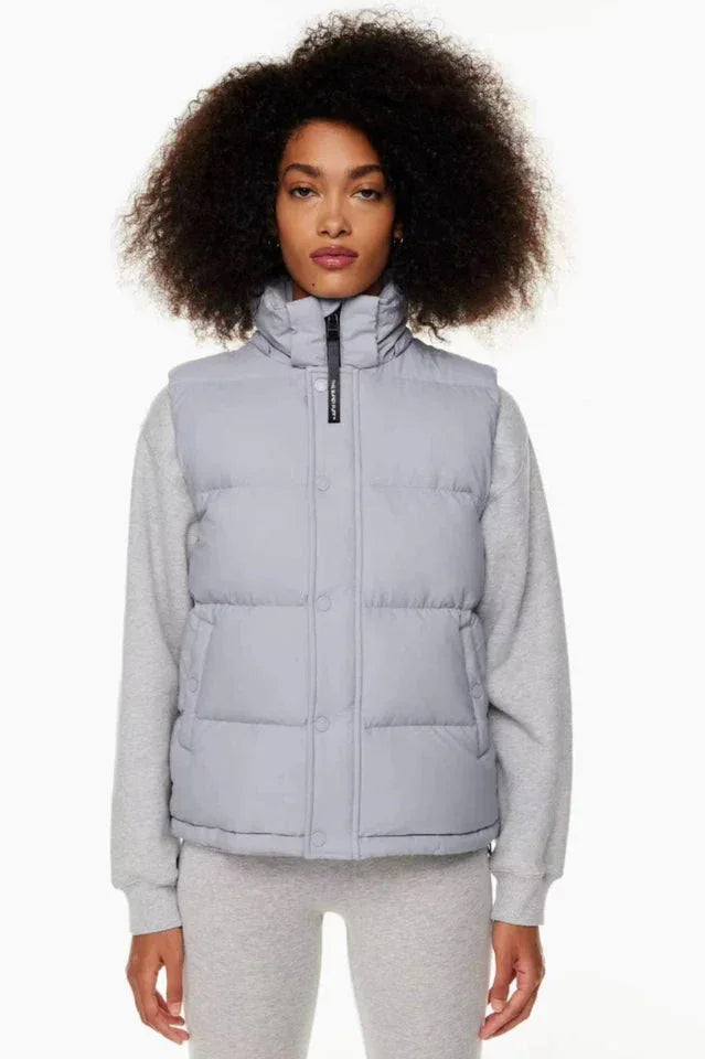 Woman wearing a light grey puffer vest over a grey sweatshirt and grey leggings