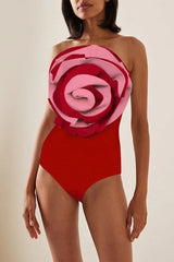 Woman wearing a red one-piece swimsuit with a pink and red floral embellishment on the bust.