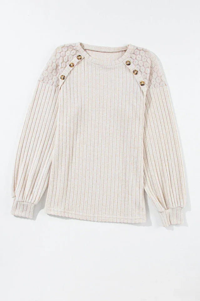 Front view of a cream ribbed knit sweater with lace shoulder detail and button accents, laid flat.