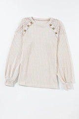 Front view of a cream ribbed knit sweater with lace shoulder detail and button accents, laid flat.