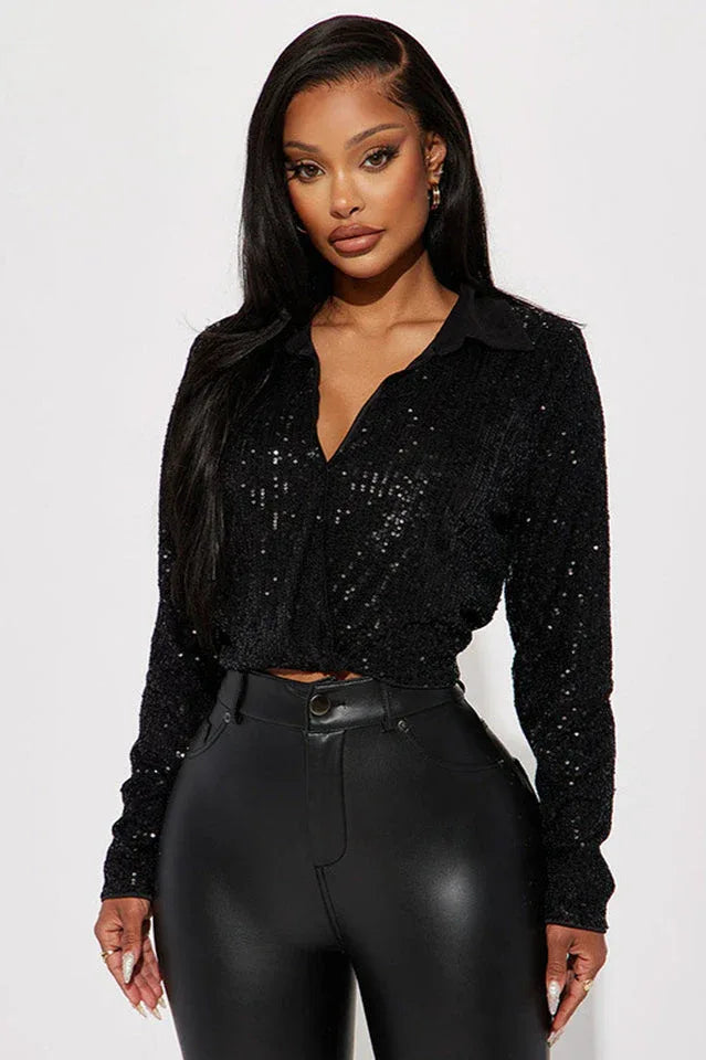 Woman wearing a black sequined cropped shirt and black faux leather pants, front view.
