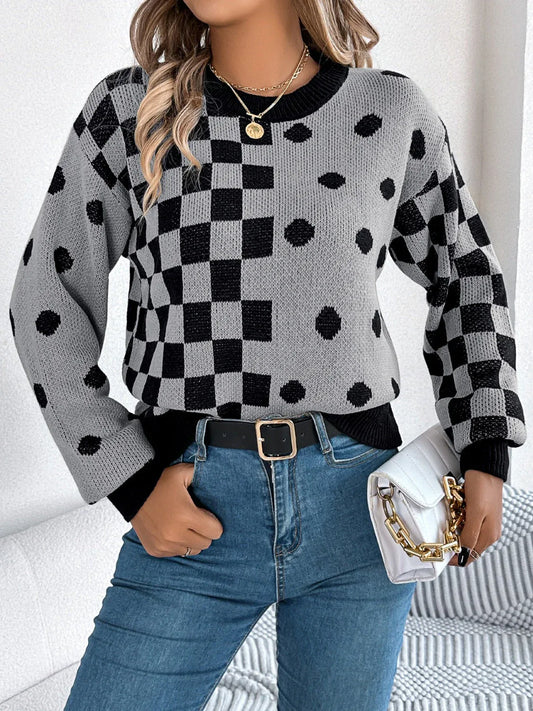 Woman wearing a gray and black checkerboard and polka dot knit sweater with blue jeans and a white handbag