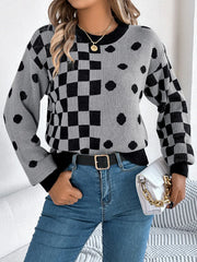 Woman wearing a gray and black checkerboard and polka dot knit sweater with blue jeans and a white handbag
