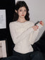 Woman wearing a white long-sleeved top with ruffled trim and beaded embellishments, paired with dark wash jeans.