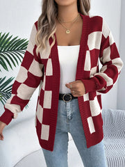 Woman wearing a red and cream checkerboard knit cardigan over a white tank top and blue jeans.