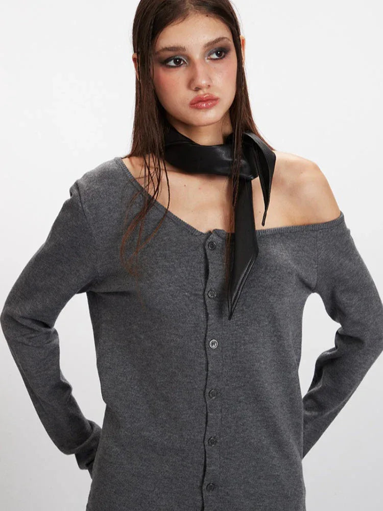 Detailed view of the model's upper body, showcasing the grey off-the-shoulder knit top and black scarf.