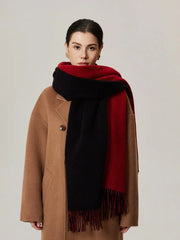 Woman wearing a camel coat and a red and black color-blocked scarf with fringe