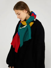 Woman looking down while wearing a black sweater and a multicolored striped knit scarf