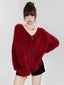 Woman wearing a fuzzy red V-neck button-up cardigan with black shorts and a silver necklace.