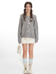 Model wearing a grey knitted cardigan with a white textured mini skirt, light blue socks, and white boots.