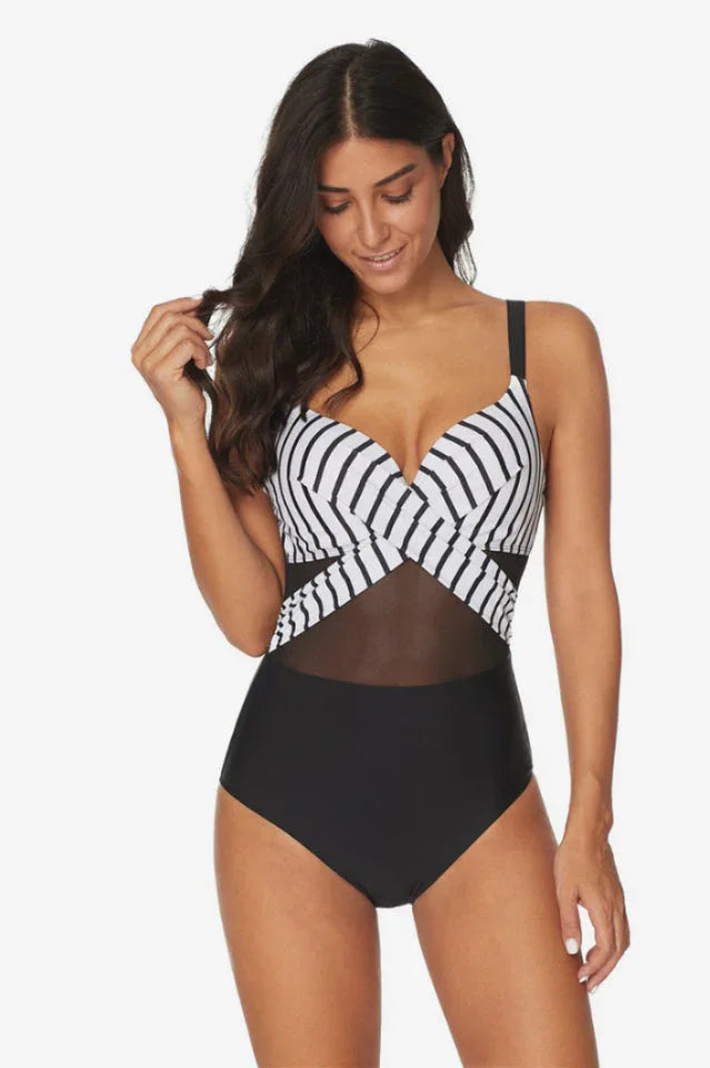 Woman posing in a black and white striped and black one-piece swimsuit with mesh detailing