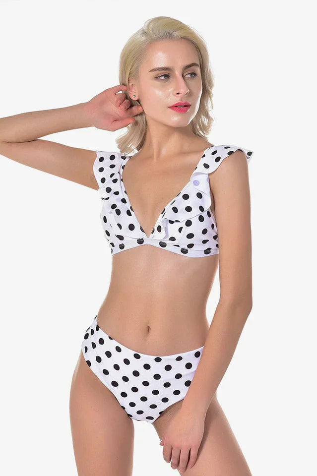 Woman with blonde hair wearing a white and black polka dot bikini with ruffled trim and high-waisted bottoms.