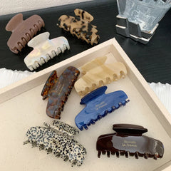 A collection of assorted hair claw clips in various colors and patterns, including tortoiseshell, leopard print, and solid colors.