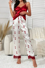 Woman wearing red satin camisole and white satin pants with red heart print and lace trim standing in a room.