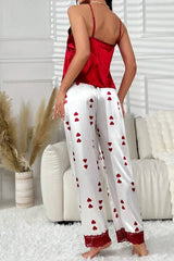 Back view of a woman wearing red satin camisole and white satin pants with red heart print and lace trim standing in a room.