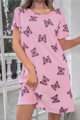 Woman wearing a pink short-sleeve nightgown with a butterfly print, standing indoors.