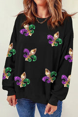 Front view of a woman wearing a black long-sleeved sweatshirt featuring a dense pattern of colorful sequin fleur-de-lis embellishments.