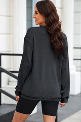 Back view of a woman wearing a charcoal ribbed long-sleeve oversized tunic and black shorts