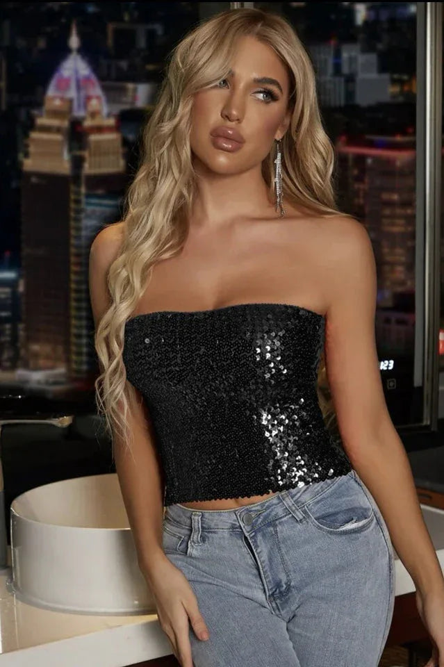 Woman wearing a black sequined strapless crop top and blue jeans