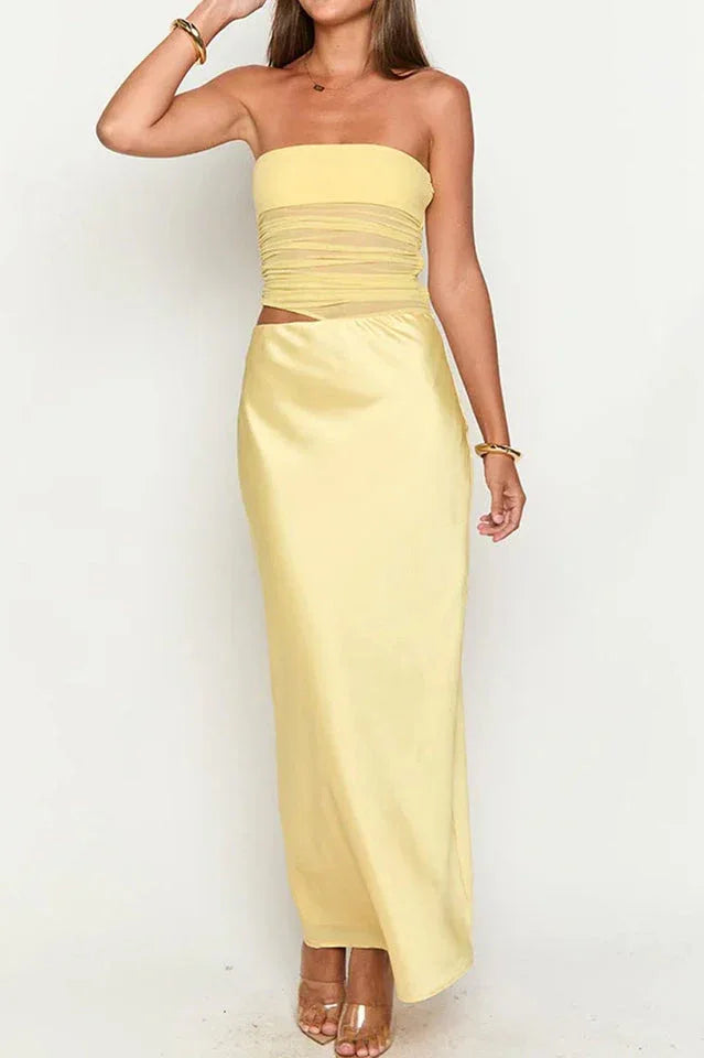 Woman posing in a yellow strapless satin maxi dress with a ruched bodice and a high slit, against a white background.