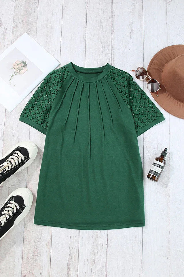 Flat lay of a green t-shirt with lace sleeves, white sneakers, sunglasses, and a hat.