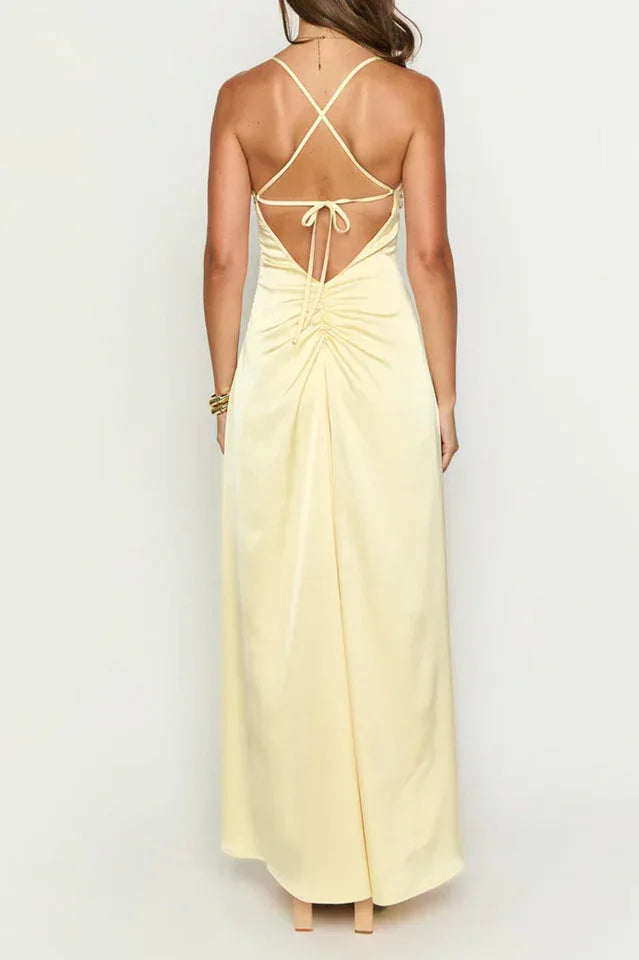 back view of a woman wearing a pale yellow satin maxi dress with spaghetti straps and a ruched back detail