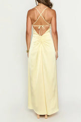 back view of a woman wearing a pale yellow satin maxi dress with spaghetti straps and a ruched back detail