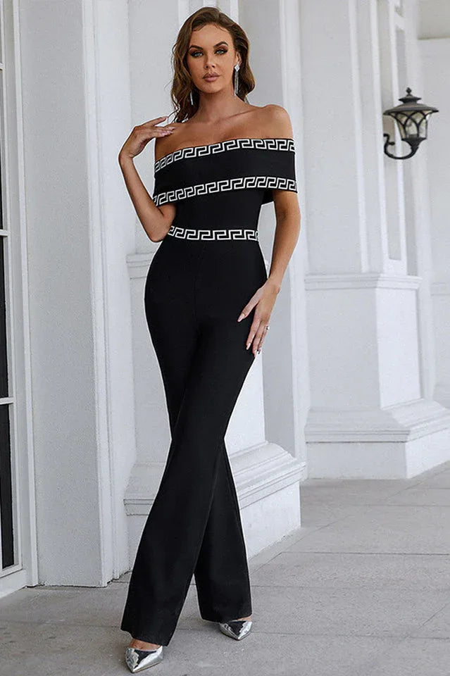 Woman in a black off-the-shoulder jumpsuit with geometric trim posing outdoors.