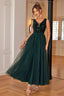 Woman in a floor-length dark green sequined and tulle formal dress with a v-neckline, shown from the front.