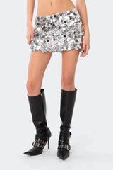Close-up of a woman's lower body wearing a silver sequined mini skirt and black boots.