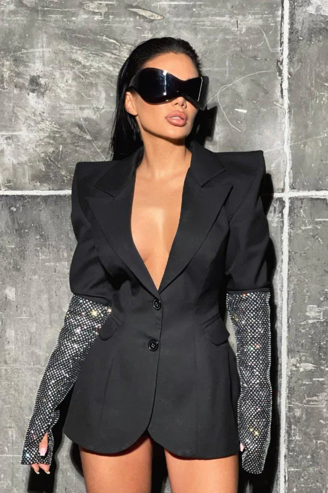 Close-up of a woman wearing a black blazer with embellished sleeves and futuristic sunglasses