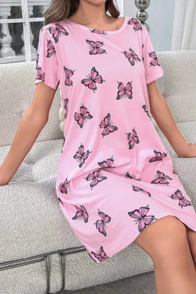 Woman wearing a pink short-sleeve nightgown with a butterfly print, sitting on a sofa.