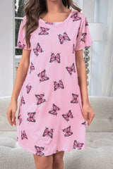 Front view of a woman wearing a pink short-sleeve nightgown with a butterfly print, indoors.