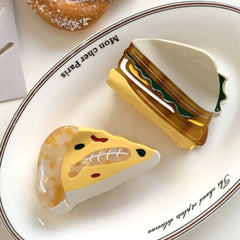 acrylic slice of pizza hair clip and a sandwich hair clip on a white plate with text that says 'Mon cher Paris'