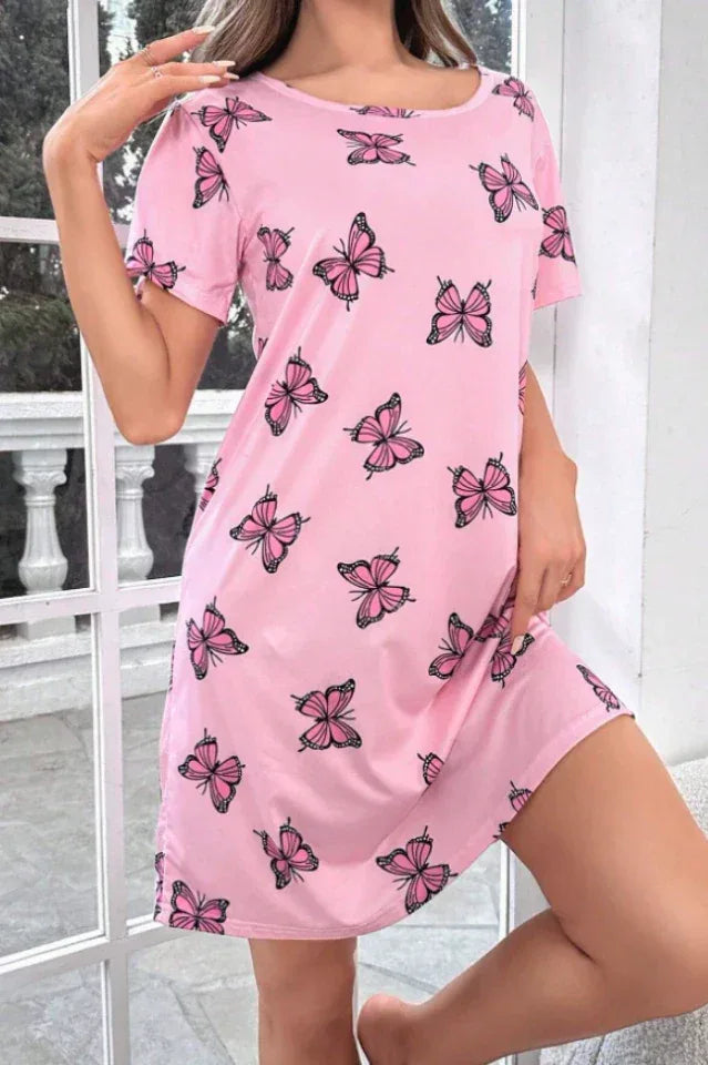 Woman wearing a pink short-sleeve nightgown with a butterfly print, posing indoors.